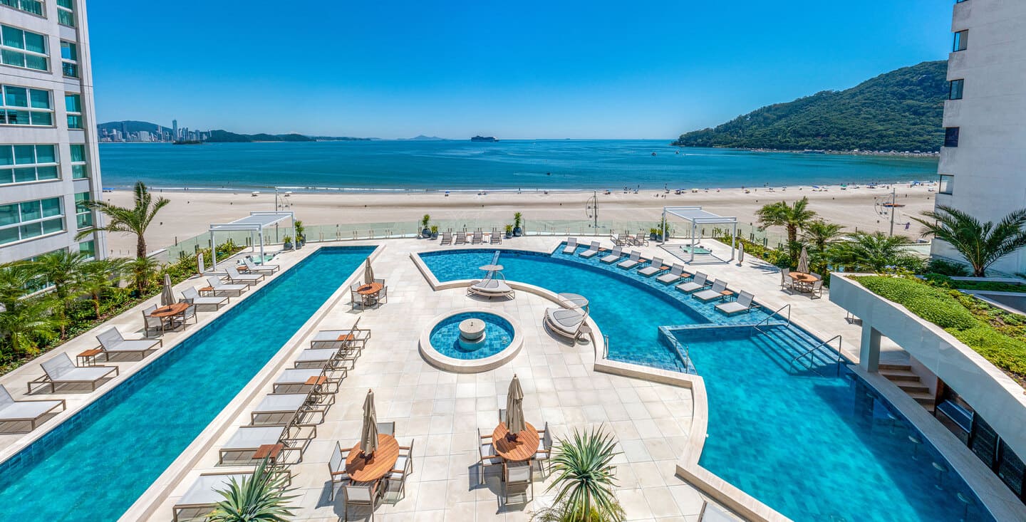 Outdoor oceanfront pool complex of One Tower featuring relaxation decks and palm trees