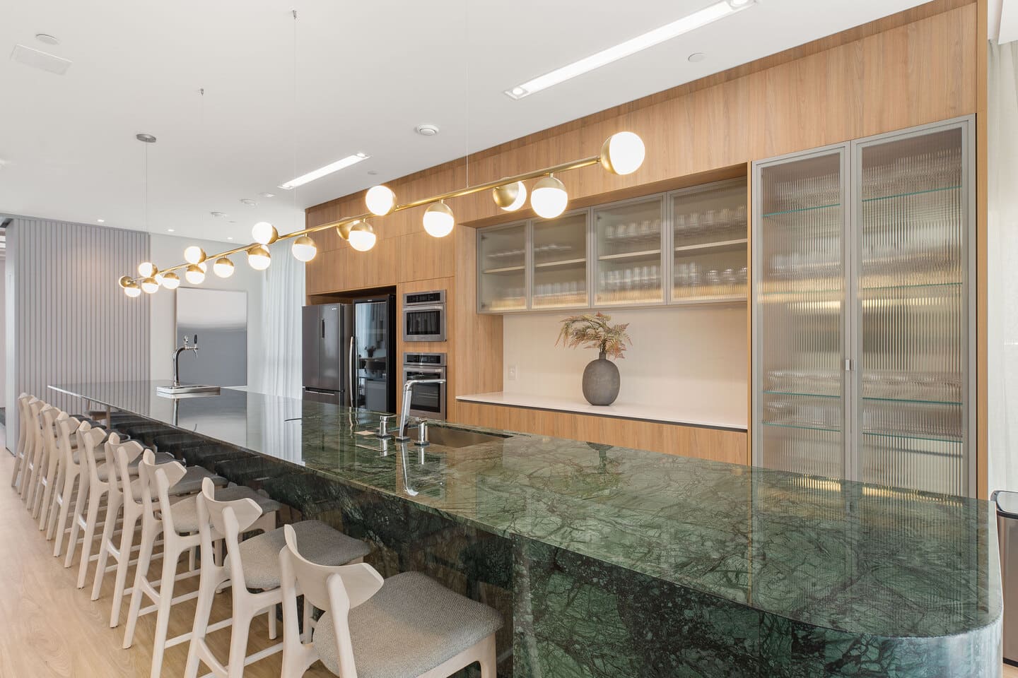 Gourmet lounge with central island in Verde Alpi marble, upholstered barstools, and contemporary finishes