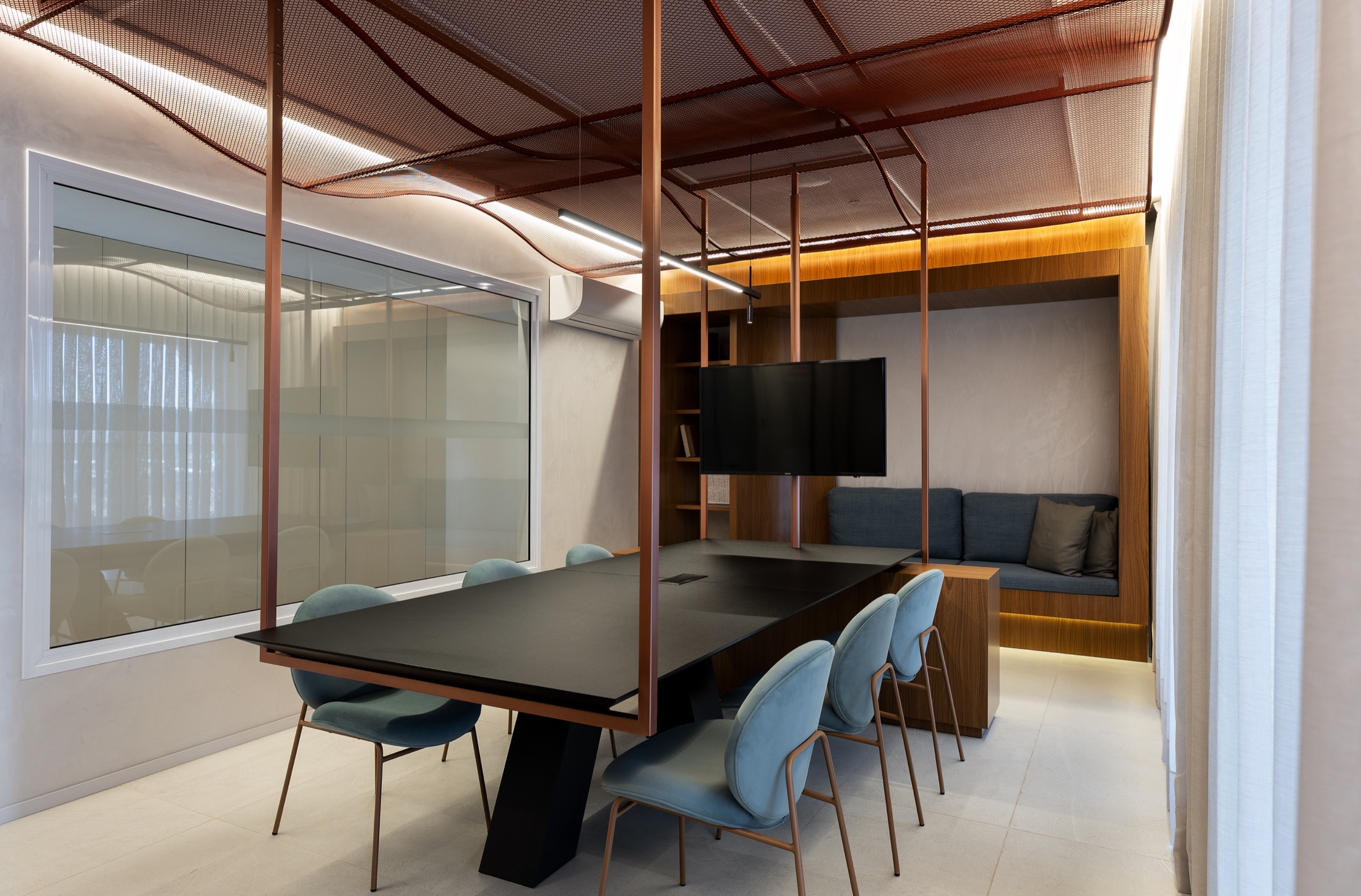 Fotografía real del Coworking con mesa suspendida por estructura metálica cobriza y techo en malla expandida