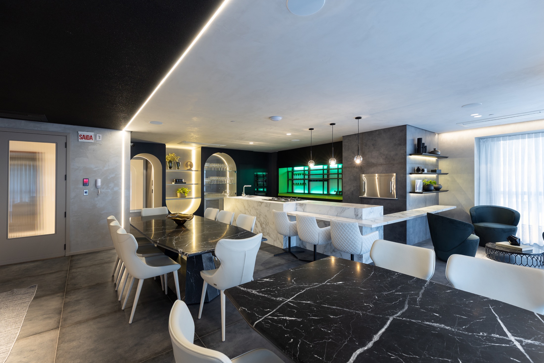 Fotografía real del Gourmet Nero con mesas en mármol negro, isla en piedra clara, vitrina iluminada en verde esmeralda y sillas firmadas Tonino Lamborghini
