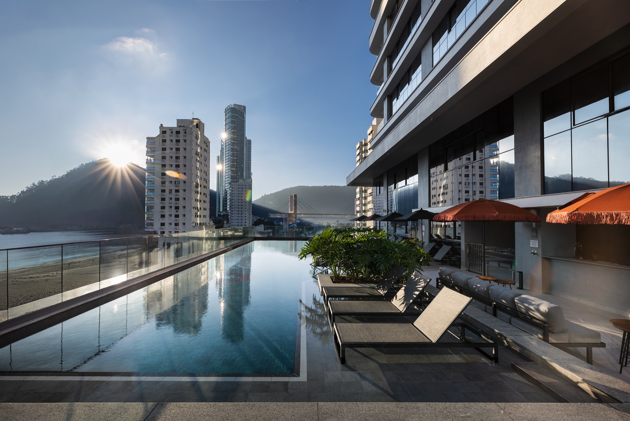 Fotografía real de la piscina exterior con borde infinito al atardecer en Barra Sul, Balneário Camboriú
