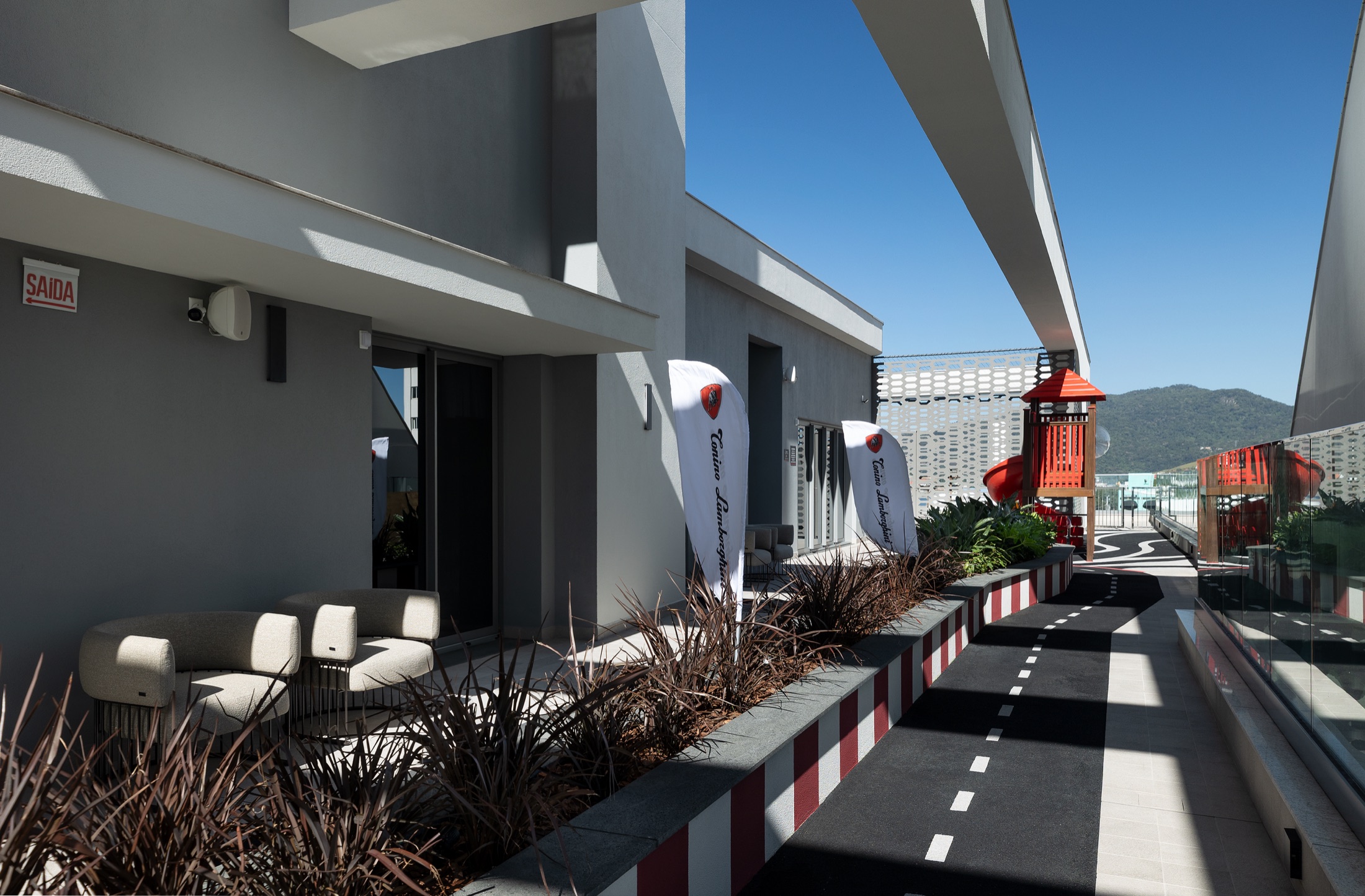 Fotografía real de la pista infantil exterior con pianos rojo y blanco estilo autódromo y banderas Tonino Lamborghini
