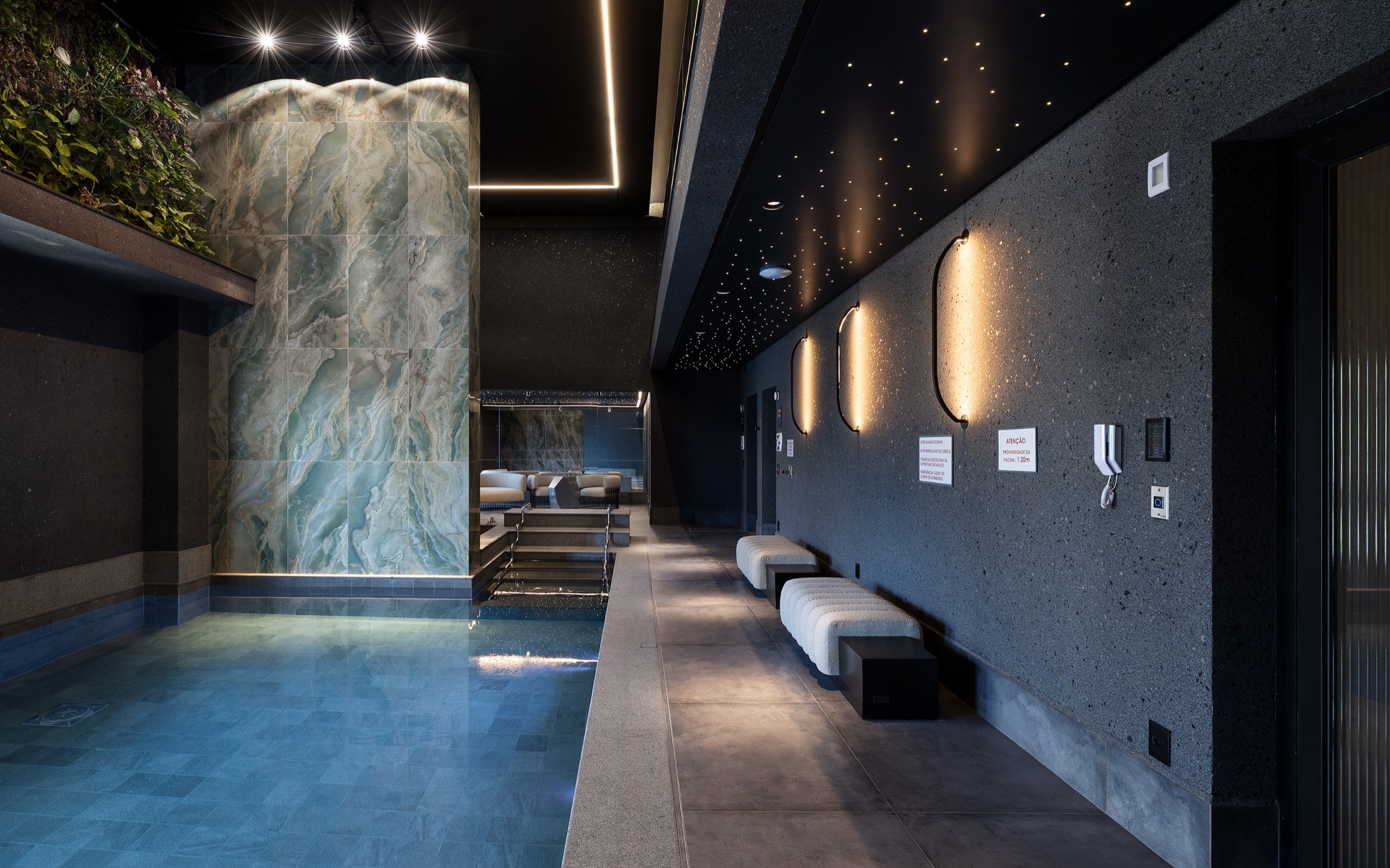 Fotografía real de la piscina climatizada e hidromasaje interior revestida en piedra natural e iluminación lineal